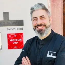 Chef Flavio Fermi vor dem Ackermannshof Basel, lächelnd in Kochjacke neben dem Michelin 2024 Schild an der Restaurant Wand