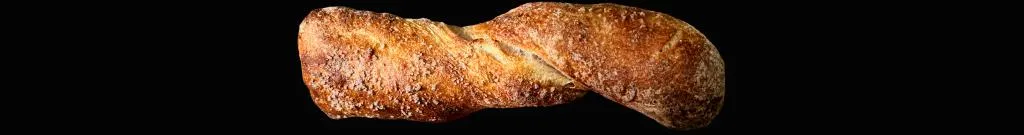 Laugenbestäubtes Brötchen mit rustikaler Kruste, gezwirbelt, leicht mehlig und mit Fleur de Sel bestreut, seitlich liegend.